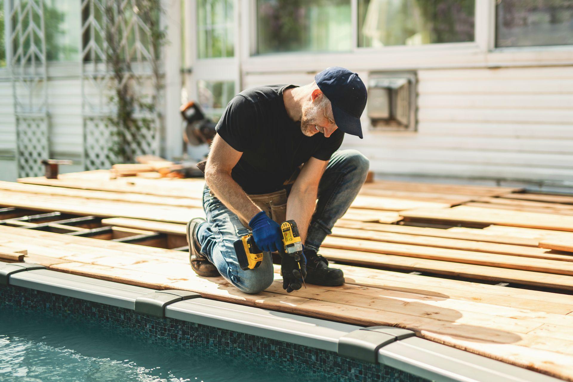 Mann montiert Holzdielen an einem Stahlwandpool – Beispiel fuer Selbstbau und individuelle Poolgestaltung
