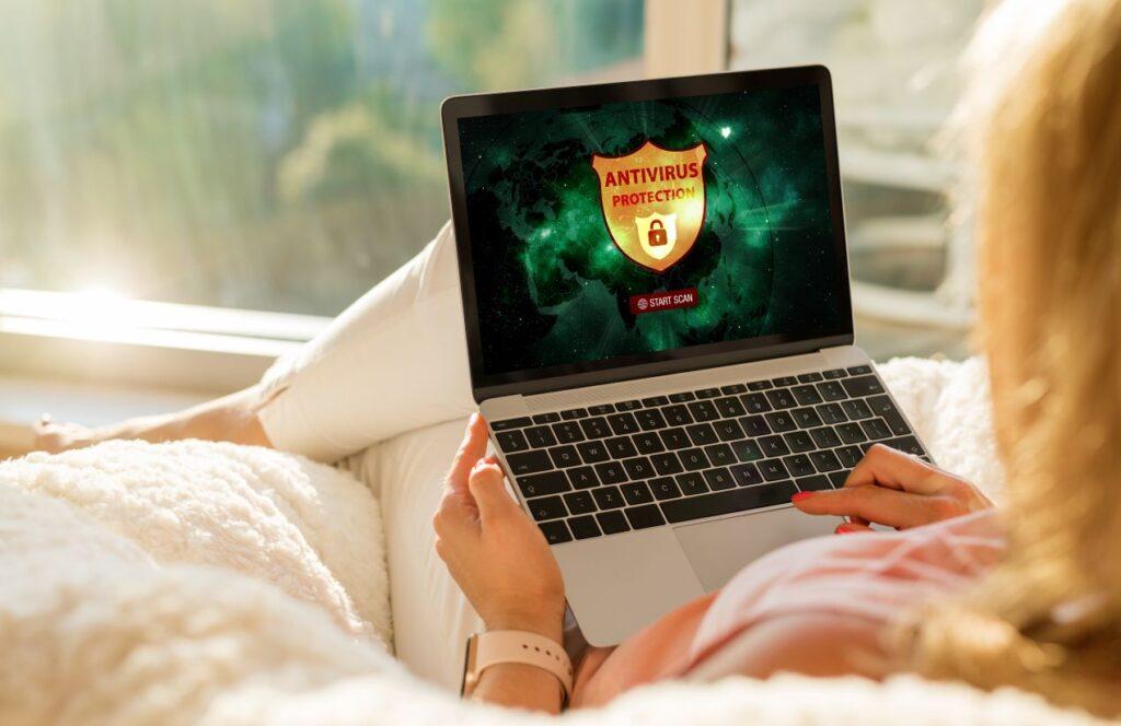 Person nutzt Laptop mit Antivirus-Schutz auf dem Bildschirm – Schutzmassnahmen, um Macbook Reparatur zu verhindern
